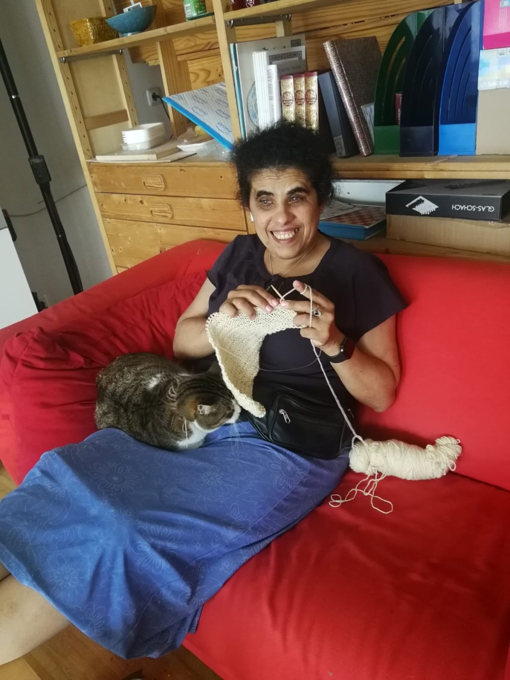 Foto Lydia sitzt strickend mit einer Katze auf dem Schoß auf einem Sofa